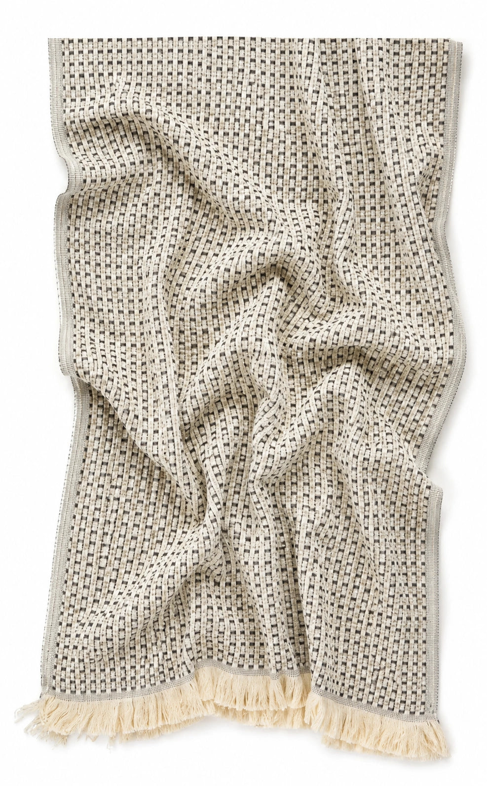 Full view of Maya cotton throw blanket showing its cream and charcoal textured weave, neutral geometric pattern and fringe trim.