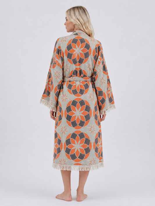 Back view of a long orange and grey jacquard cotton kimono robe featuring large geometric floral patterns, a matching belt, wide sleeves, and fringed edges.