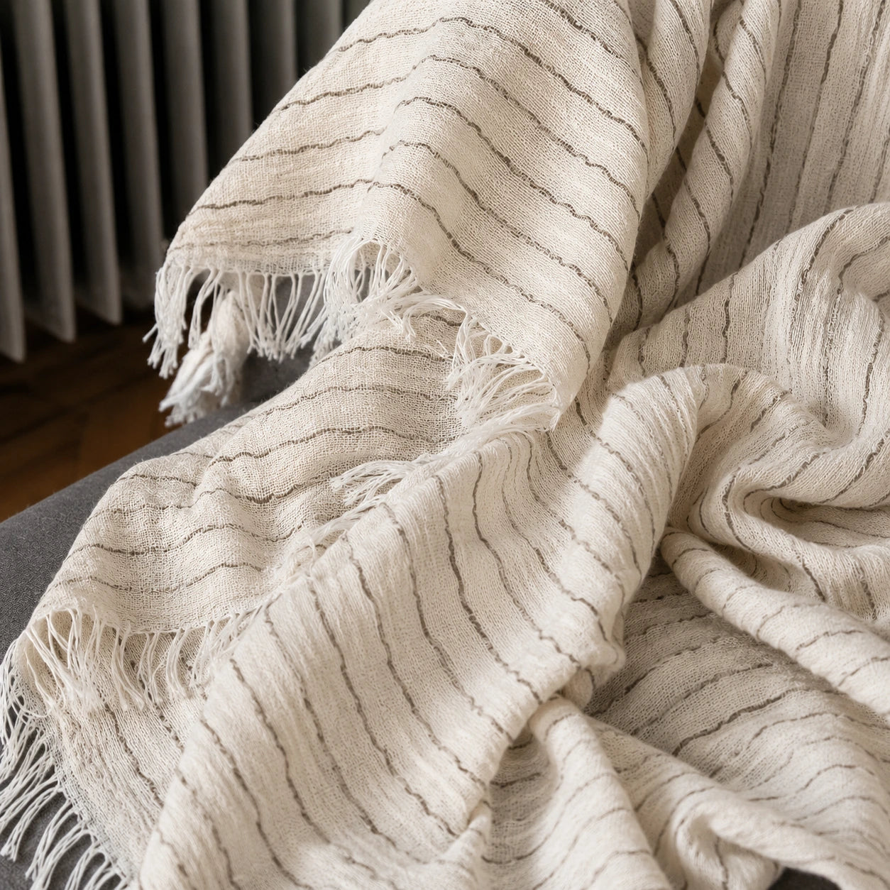 Close-up of the Heidi cotton throw blanket showing its breathable woven texture, fine neutral stripes and soft fringe.