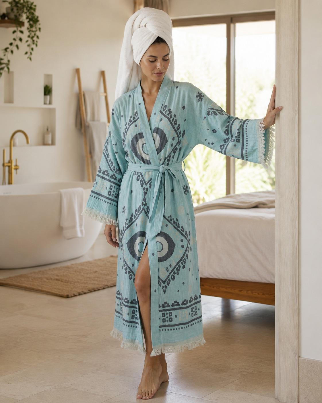 A woman wearing a light blue patterned bathrobe with a matching tie belt and a white towel wrapped around her head.