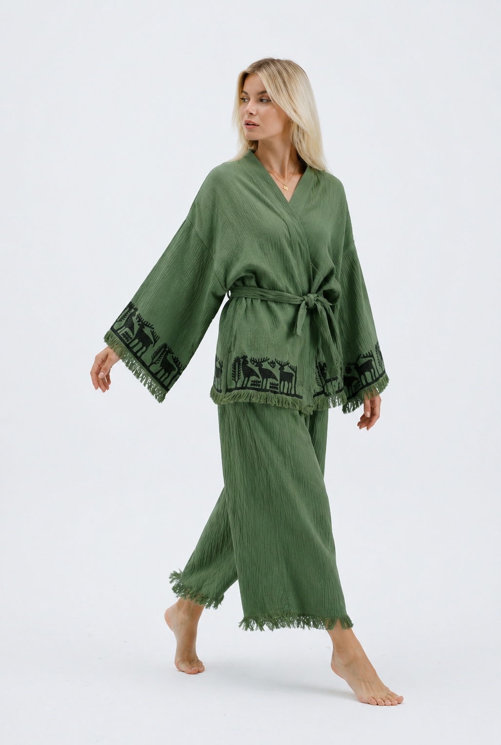Model in sage green cotton kimono jacket and wide-leg pants set with black animal border motifs and fringed hems.