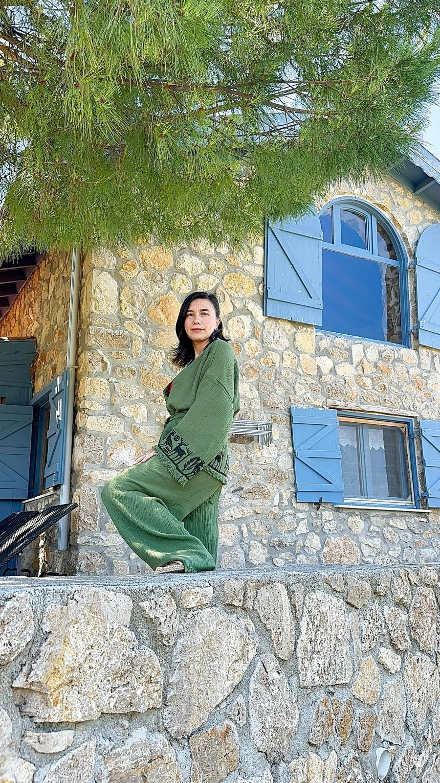 A woman wearing Nara kimono set  posing outdoors on a stone wall in front of a stone building. 