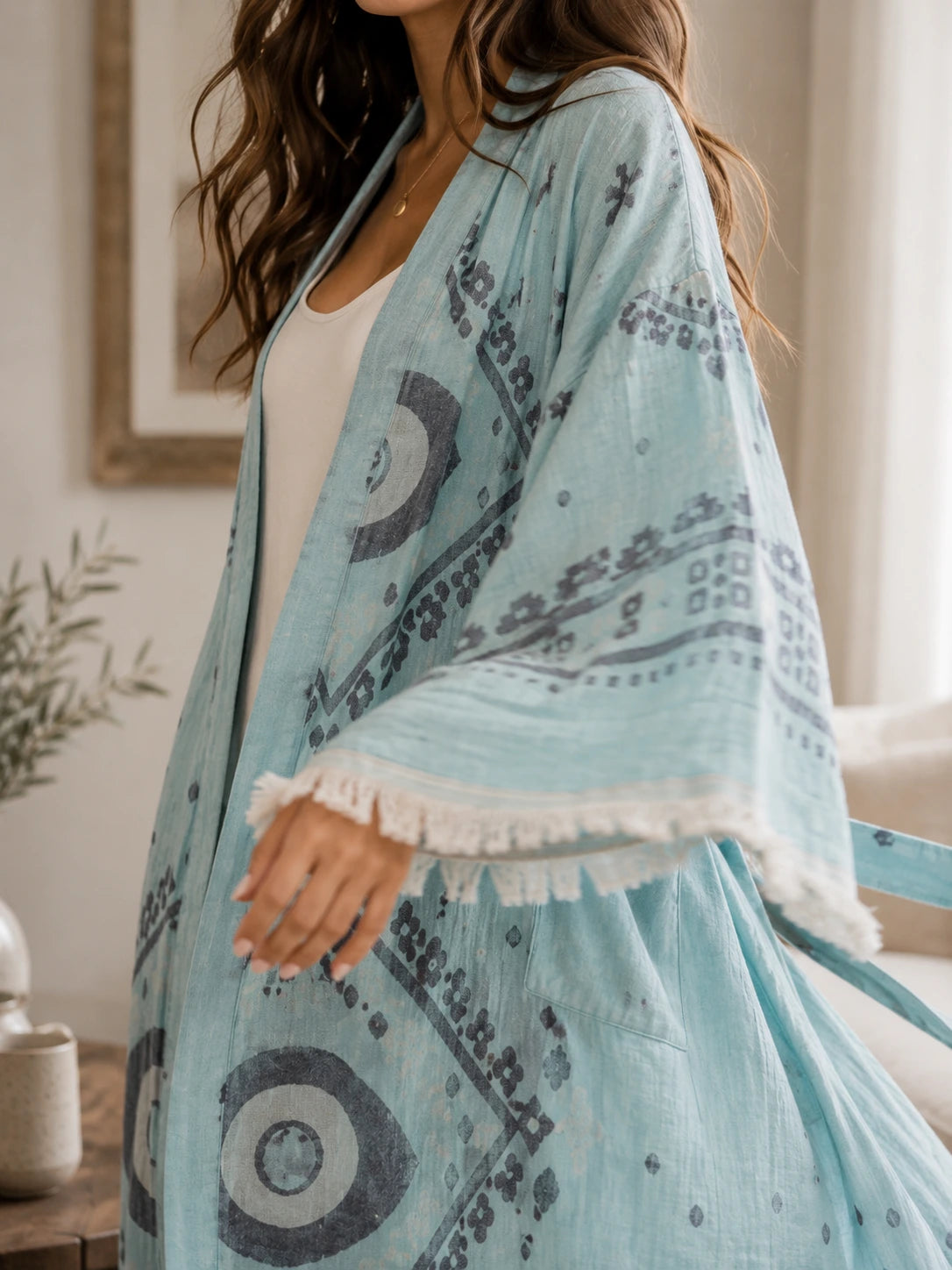 Close-up of Ocean cotton kimono robe in soft blue with woven evil eye motifs, charcoal details and hand-finished fringe sleeves.
