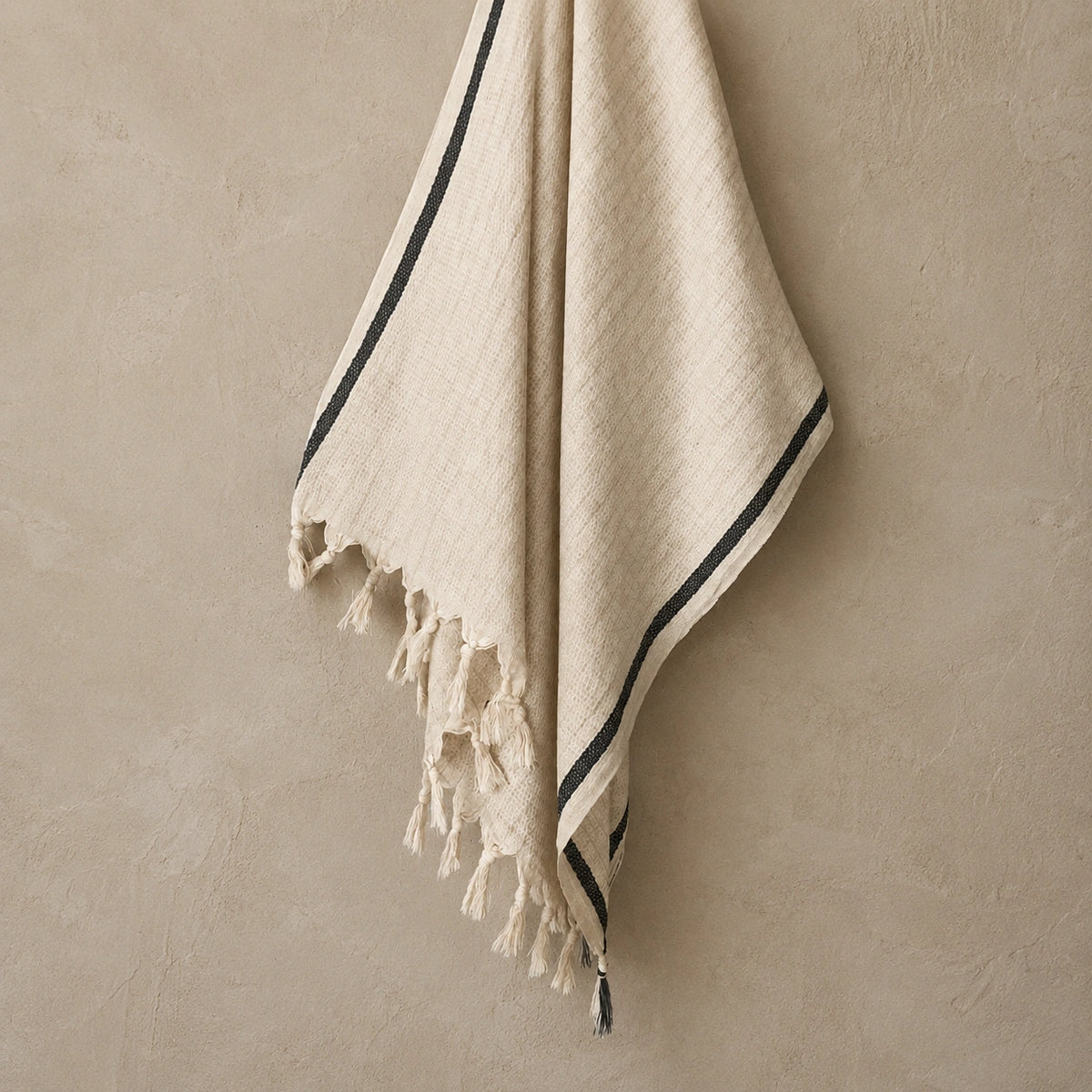 Alara cotton linen Turkish towel in natural ivory with black stripe, textured weave and hand-finished tassel fringe.