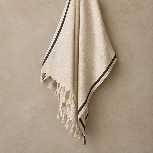 Alara cotton linen Turkish towel in natural ivory with black stripe, textured weave and hand-finished tassel fringe.
