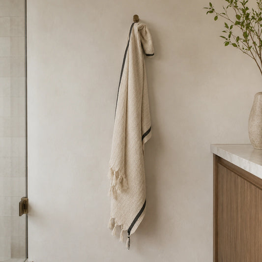 Lightweight Alara cotton linen Turkish towel hanging in a neutral bathroom, showing its long size and black border.