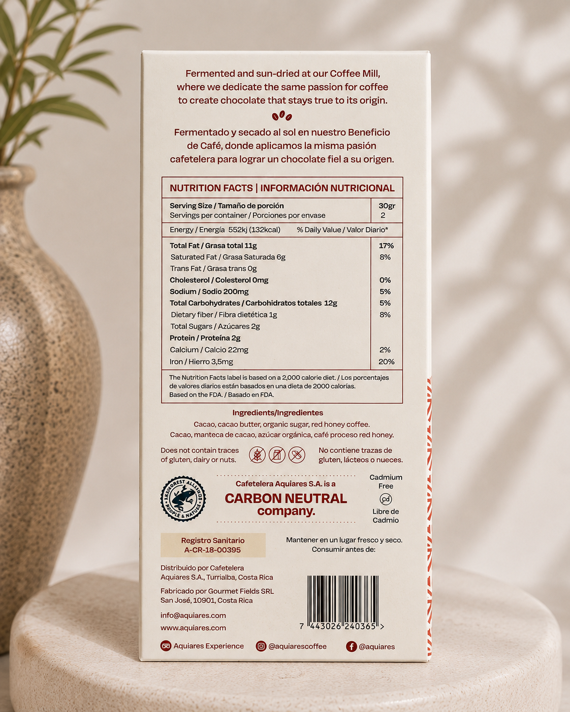 The back of a coffee milk package, showing nutrition facts, ingredients, and carbon neutral certification details, photographed against a soft beige fabric background with a leaf at the top left.