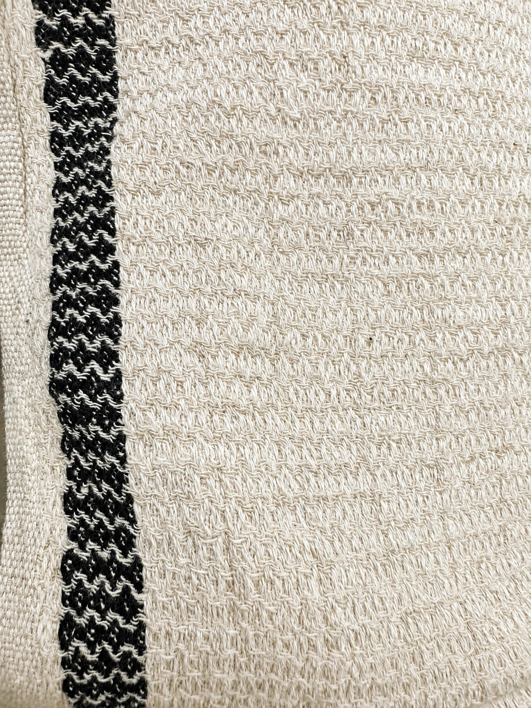 Close-up of Bella Turkish cotton towel showing its textured natural ivory weave and contrasting black woven stripe.