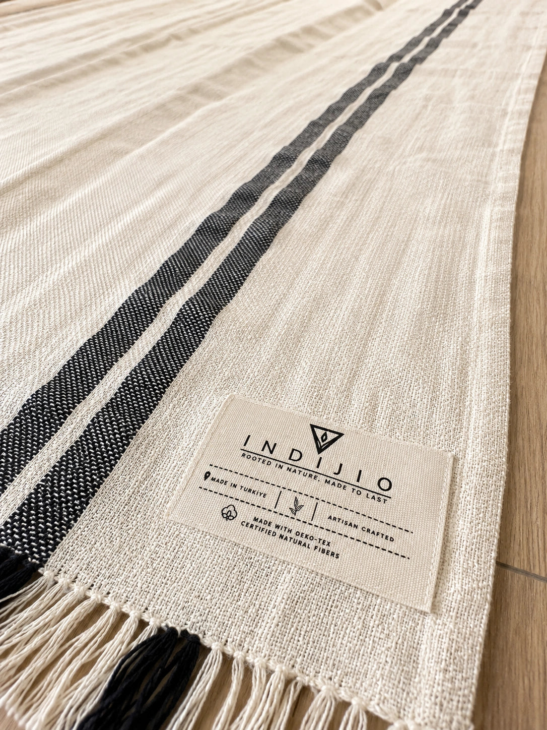 Close-up of Celine cotton Turkish towel showing its natural ivory woven texture and contrasting double black stripes.