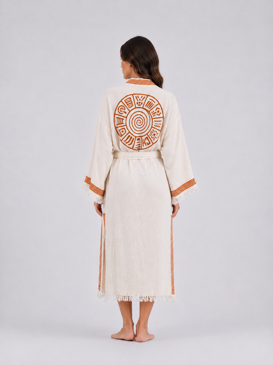 Full back view of a cream textured cotton kimono robe featuring a large burnt-orange circular spiral motif, geometric collar and side trim, wide fringed sleeves, and a matching waist belt.