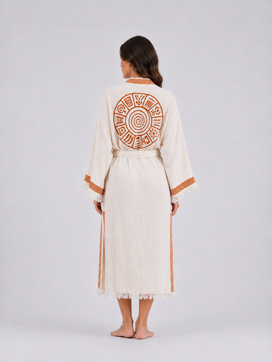Full back view of a cream textured cotton kimono robe featuring a large burnt-orange circular spiral motif, geometric collar and side trim, wide fringed sleeves, and a matching waist belt.