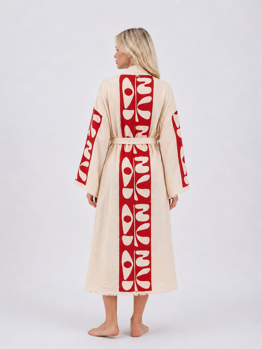 Full back view of a cream cotton kimono robe featuring a bold vertical red abstract design across the back and sleeves, a matching tie belt, wide sleeves, and softly fringed edges.