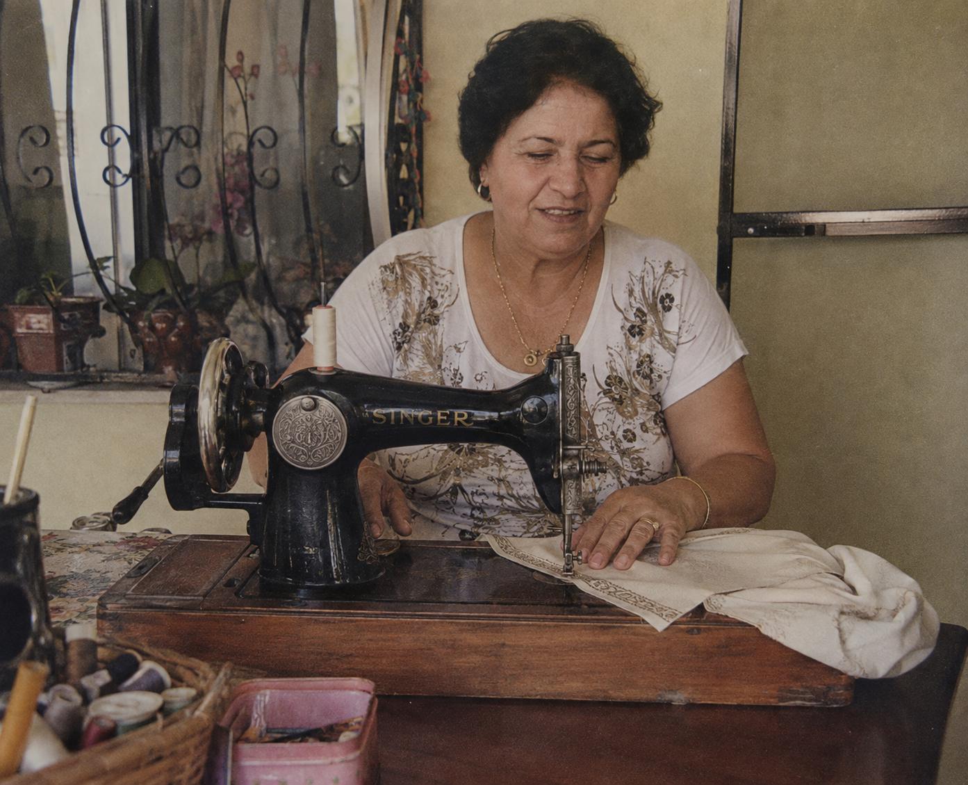 Artisan seamstress sewing cream fabric with gold trim on a vintage Singer sewing machine — Indijio craftsmanship
