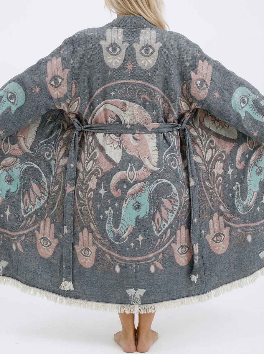 Close-up back view of a grey jacquard cotton kimono robe featuring detailed pink and turquoise elephant motifs, Hamsa hands, evil eye symbols, stars, a matching belt, and fringed hem.