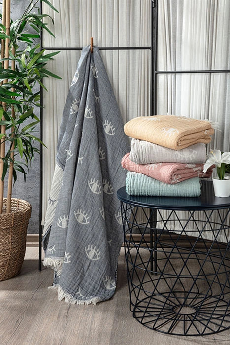 Lia Turkish cotton peshtemal towels displayed in grey, yellow, rose, mint and neutral colors with woven eye motifs.
