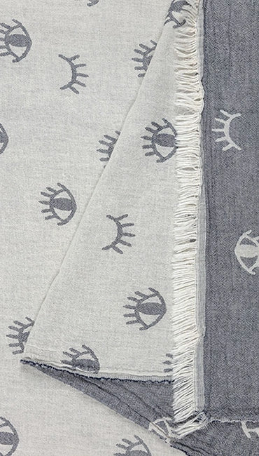 Lia navy Turkish cotton peshtemal towel showing its charcoal eye motif, contrasting woven reverse and fringed edge.
