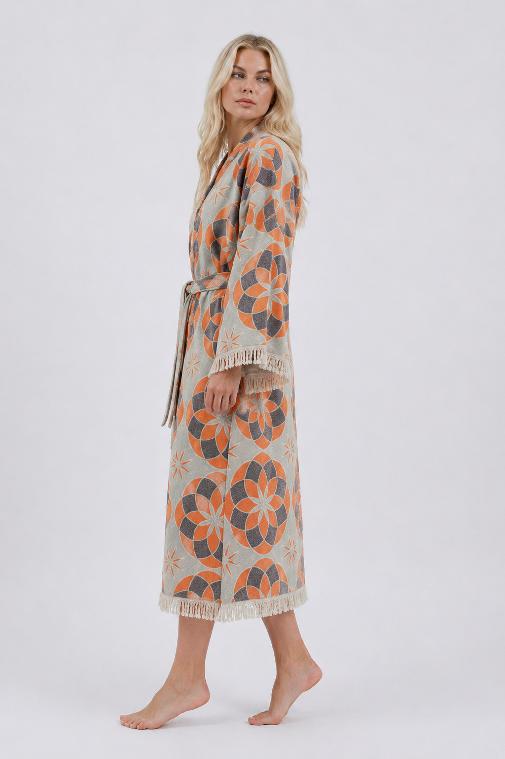 Side view of an orange and grey jacquard cotton kimono robe showing its relaxed ankle-length fit, wide fringed sleeves, matching belt, and bold floral design.